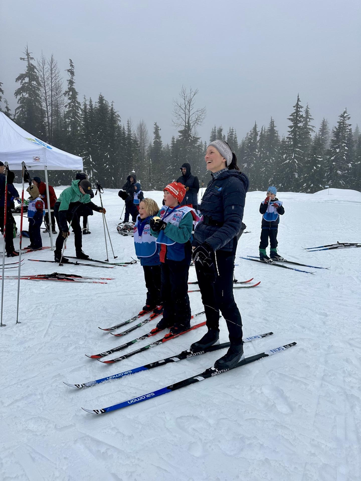 Cross-country skiers standing on snow in a wooded area. Whistler Olympic Park