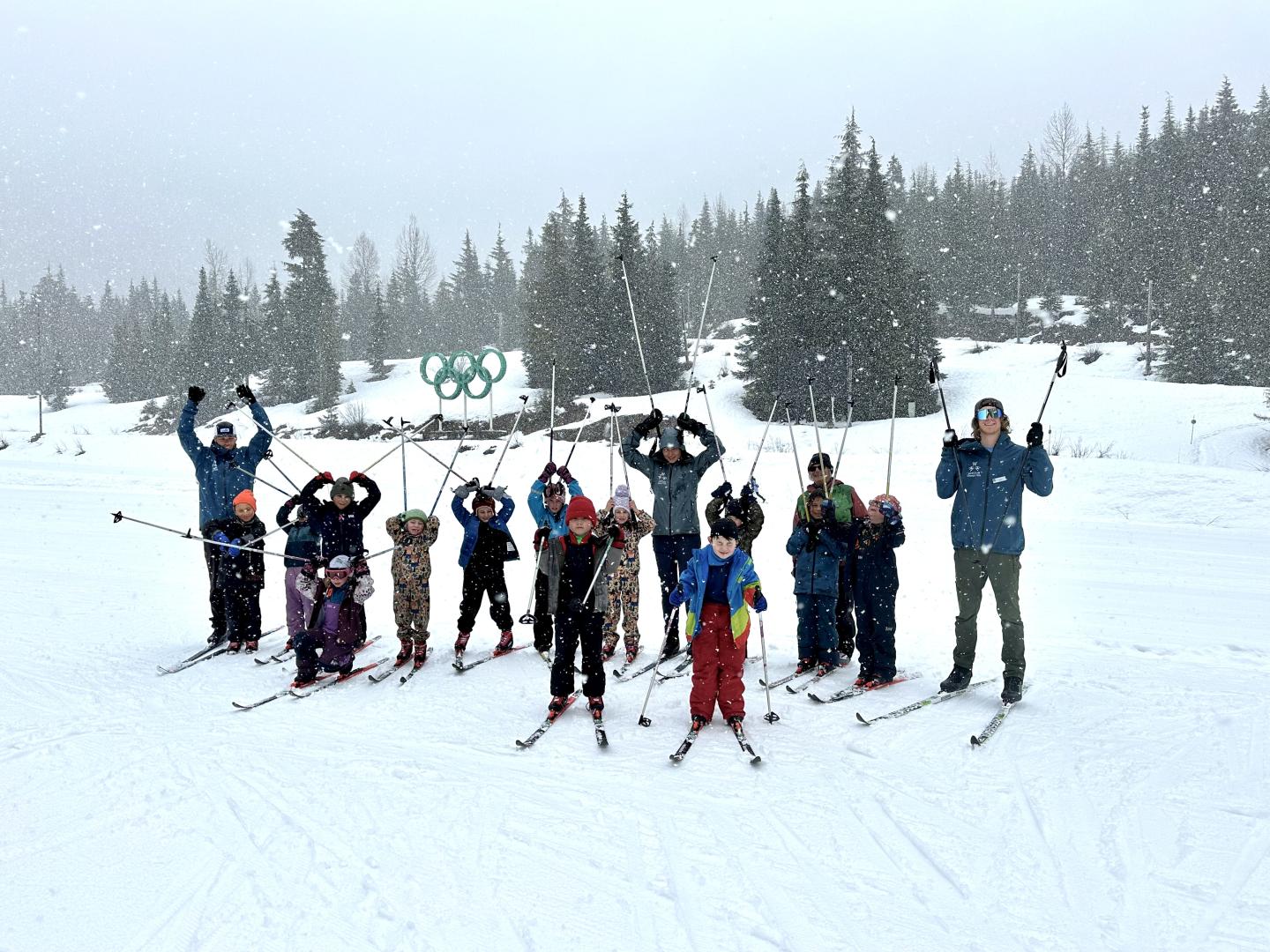 Skiers posing on snowy slope, surrounded by trees and snowflakes falling.